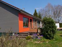 Holzfassade mit Aktzentsetzung durch orangene Fassadenplatten